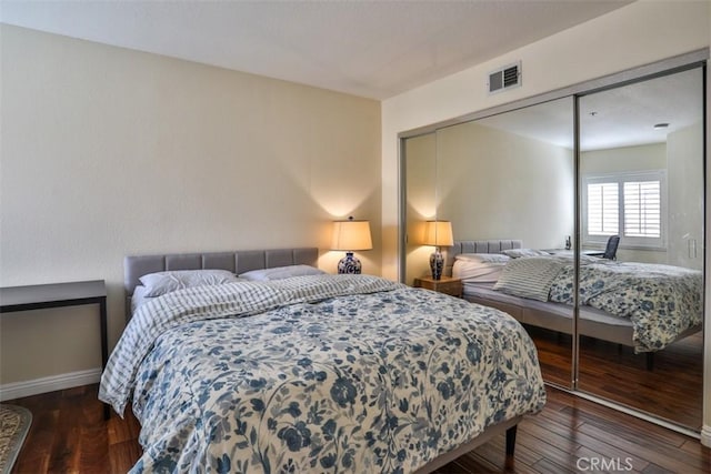 bedroom featuring baseboards, visible vents, hardwood / wood-style flooring, and a closet