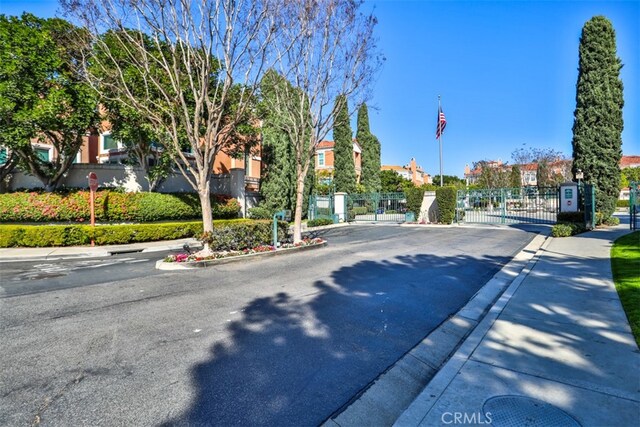 view of street featuring sidewalks, a gated entry, a gate, and curbs