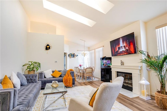 28751 Broadstone Way, Menifee, CA 92584 - living room featuring a skylight, light wood-style flooring, a chandelier, lofted ceiling, and a glass covered fireplace