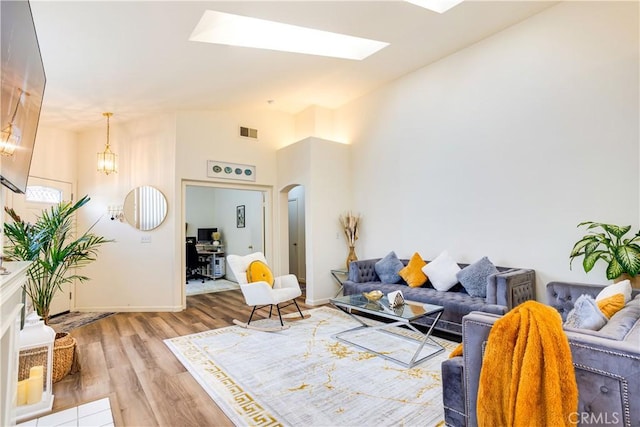 28751 Broadstone Way, Menifee, CA 92584 - living room with arched walkways, wood finished floors, a skylight, vaulted ceiling, and baseboards