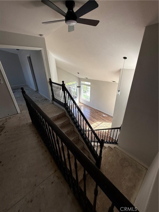 stairway featuring lofted ceiling and ceiling fan