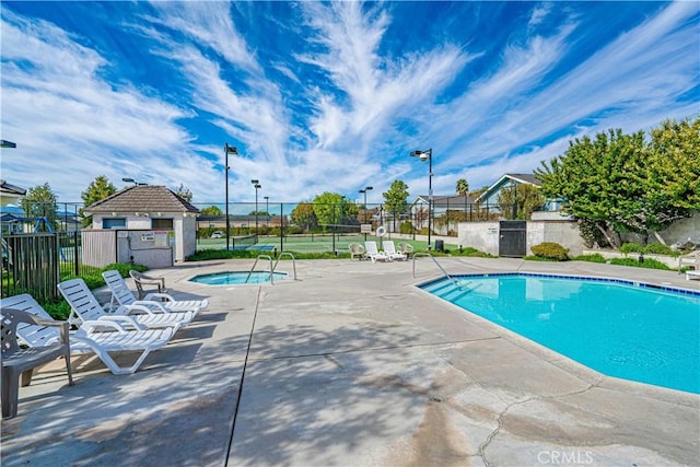 community pool with a patio area, a community hot tub, and fence
