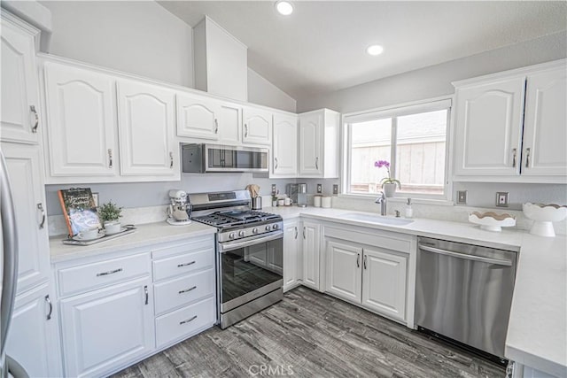 kitchen with lofted ceiling, white cabinetry, a sink, and appliances with stainless steel finishes