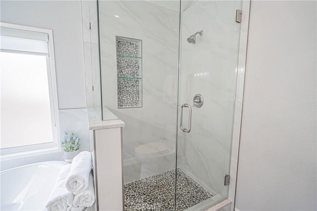 full bathroom featuring toilet, a garden tub, and a marble finish shower
