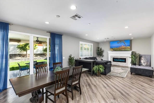 30580 Hawkscrest Rd, Murrieta, CA 92563 - dining room with a glass covered fireplace, recessed lighting, visible vents, and wood finished floors