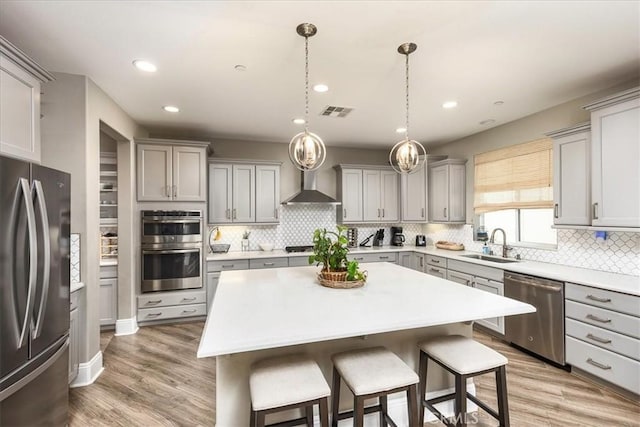 30580 Hawkscrest Rd, Murrieta, CA 92563 - kitchen with wall chimney exhaust hood, a sink, a kitchen bar, gray cabinetry, and stainless steel appliances