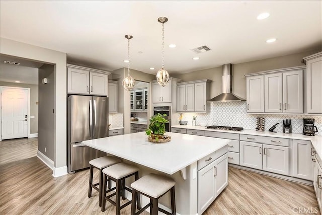30580 Hawkscrest Rd, Murrieta, CA 92563 - kitchen featuring gray cabinets, appliances with stainless steel finishes, wall chimney range hood, and visible vents