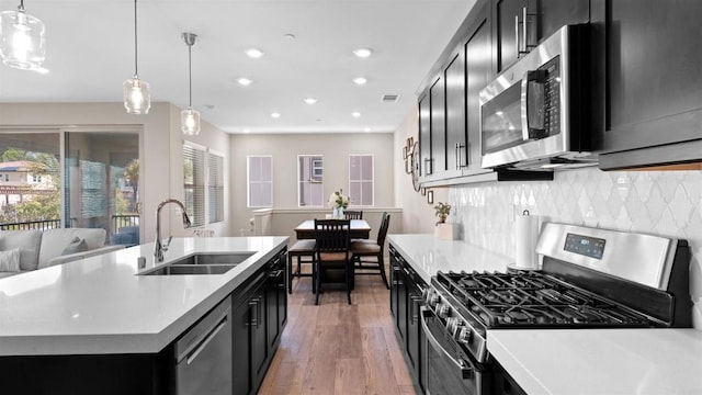 10861 Blake Way, San Diego, CA 92129 - kitchen featuring appliances with stainless steel finishes, dark cabinets, wood finished floors, light countertops, and backsplash
