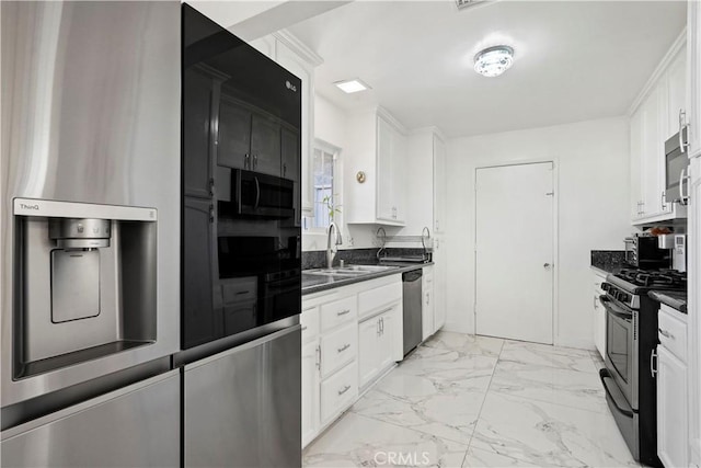 kitchen with white cabinets, marble finish floor, stainless steel appliances, dark countertops, and a sink