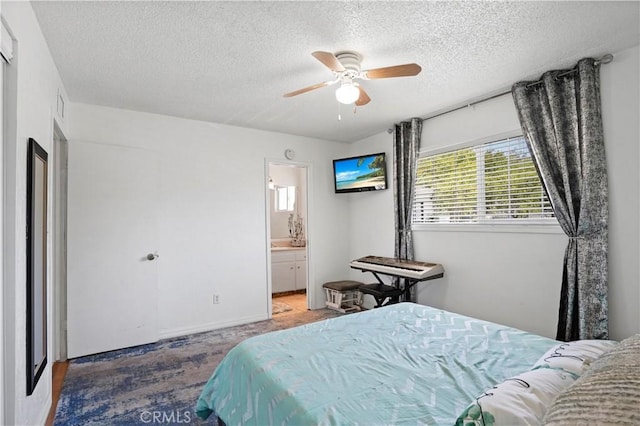 carpeted bedroom featuring ensuite bath, a ceiling fan, and a textured ceiling