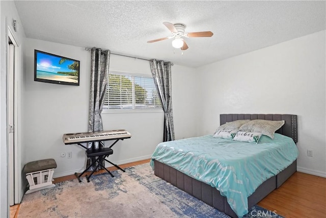 bedroom with ceiling fan, baseboards, wood finished floors, and a textured ceiling