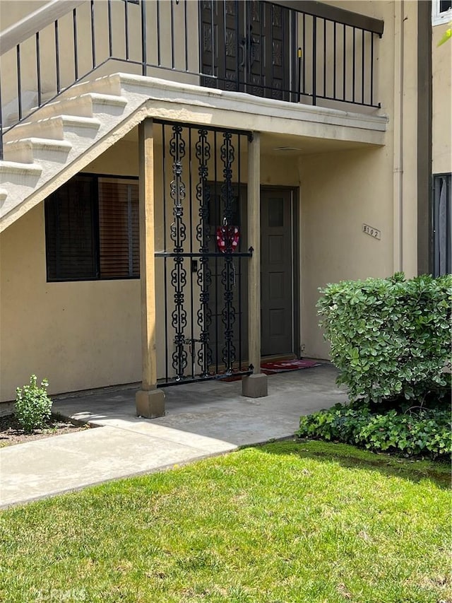 1111 S Coast Dr Unit 18, Costa Mesa, CA 92626 - entrance to property with stucco siding, a balcony, and a lawn