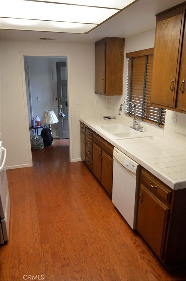 1111 S Coast Dr Unit 18, Costa Mesa, CA 92626 - kitchen featuring white dishwasher, a sink, wood finished floors, baseboards, and tile countertops