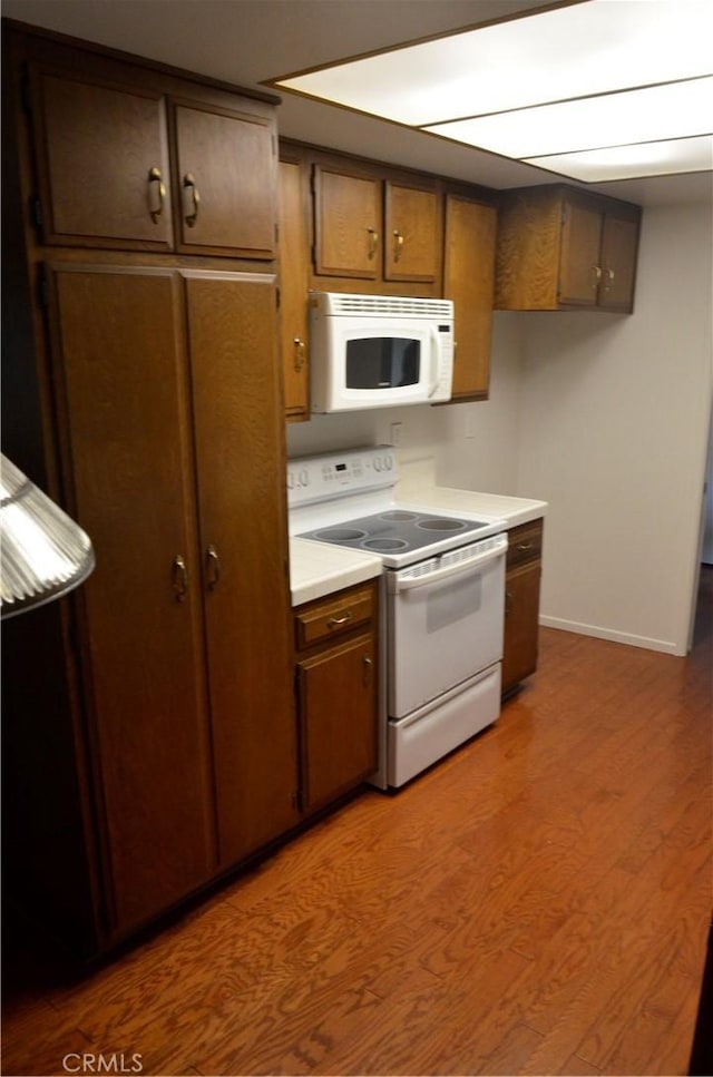 1111 S Coast Dr Unit 18, Costa Mesa, CA 92626 - kitchen featuring white appliances, wood finished floors, light countertops, and baseboards