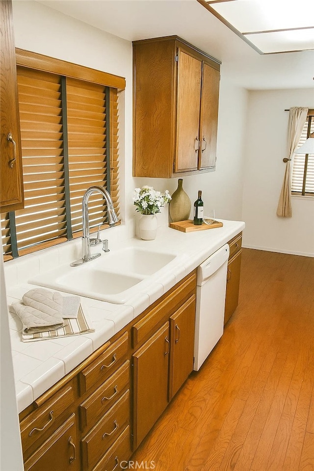 1111 S Coast Dr Unit 18, Costa Mesa, CA 92626 - kitchen with white dishwasher, light wood finished floors, brown cabinets, and tile countertops