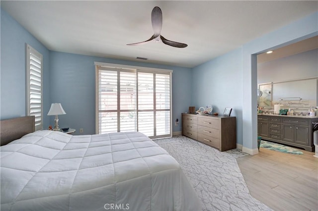 bedroom featuring light wood-type flooring, ensuite bath, a ceiling fan, visible vents, and baseboards