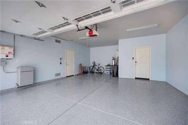 garage featuring a garage door opener, fridge, and visible vents