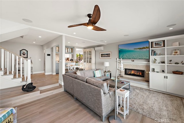 1001 Buena Vis Unit 2, San Clemente, CA 92672 - living room featuring a ceiling fan, a wall unit AC, light wood-type flooring, stairway, and a glass covered fireplace