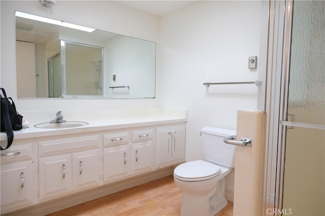 bathroom featuring toilet, vanity, and a stall shower