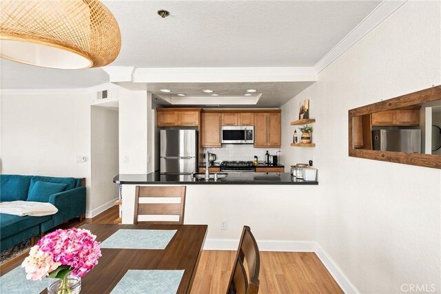 1100 Euclid Ave Unit 103, Long Beach, CA 90804 - kitchen featuring appliances with stainless steel finishes, wood finished floors, dark countertops, ornamental molding, and brown cabinets