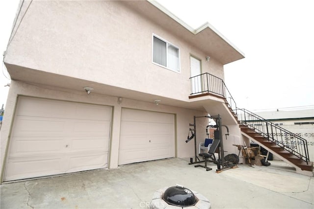 view of side of home featuring an attached garage, stairs, and stucco siding