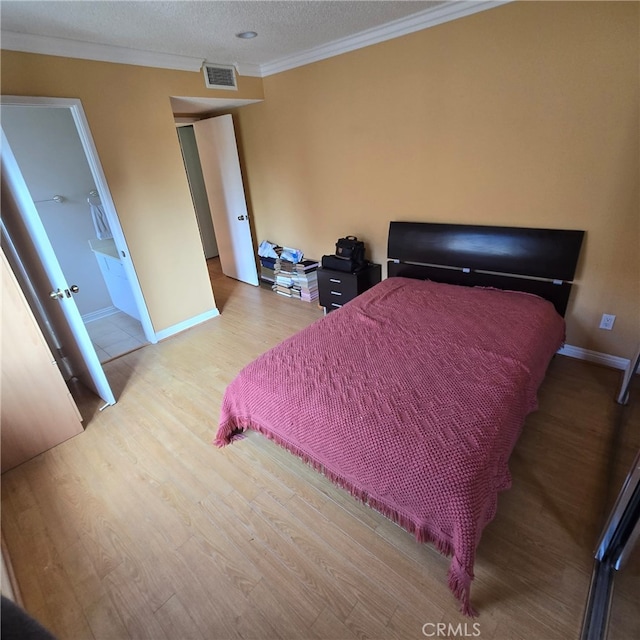 bedroom with visible vents, ornamental molding, baseboards, and wood finished floors