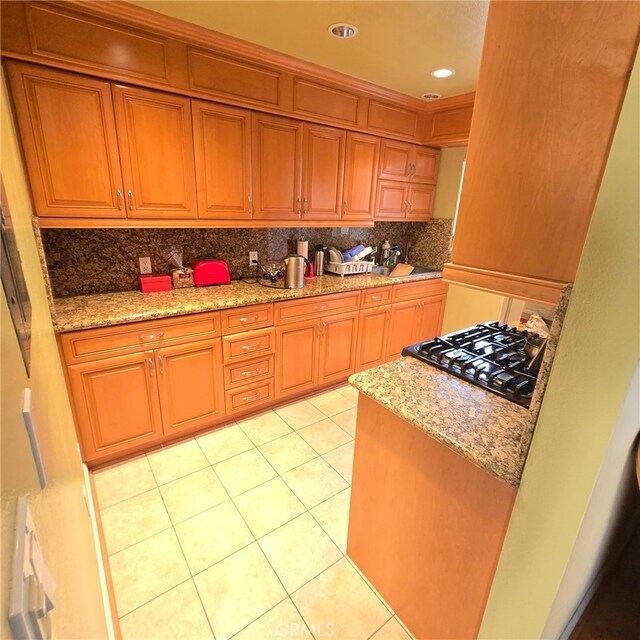 kitchen featuring light stone counters, tasteful backsplash, stove, and light tile patterned flooring