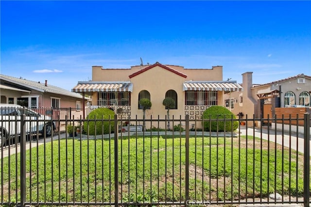 mediterranean / spanish-style home with a front yard, a residential view, stucco siding, and a fenced front yard