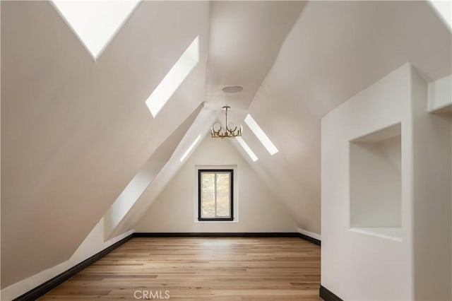 729 Brentwood Dr, Lake Arrowhead, CA 92352 - bonus room with lofted ceiling with skylight, baseboards, an inviting chandelier, and wood finished floors