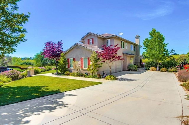 traditional-style house featuring a chimney, a front lawn, driveway, a garage, and stucco siding