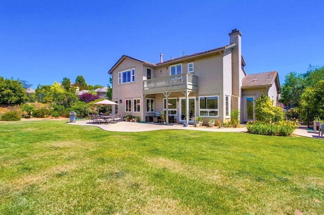 back of property featuring stucco siding, a lawn, a patio, and a balcony