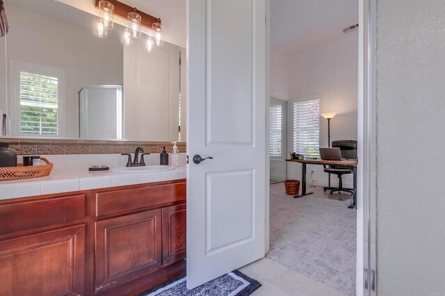 bathroom featuring visible vents, an enclosed shower, and vanity
