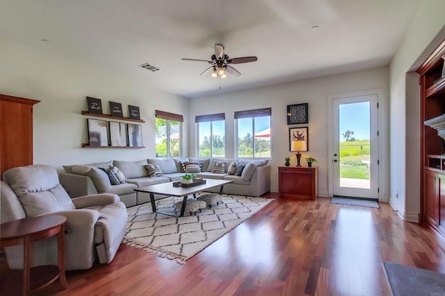 living area with wood finished floors, visible vents, baseboards, and ceiling fan