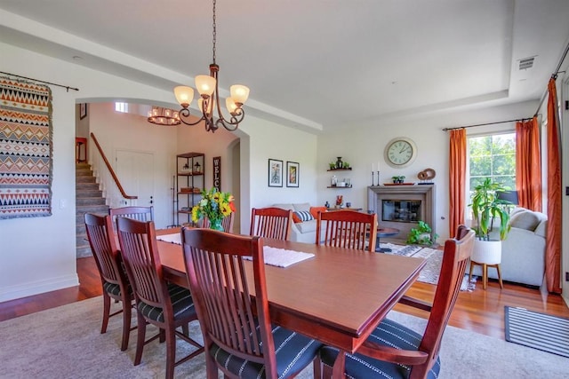 dining area with arched walkways, wood finished floors, and visible vents