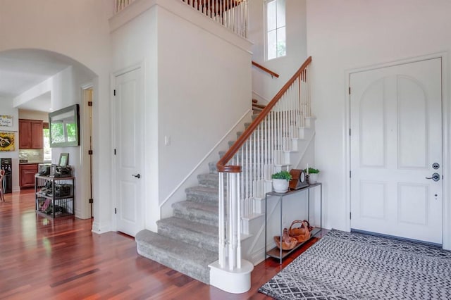 entrance foyer featuring wood finished floors, a high ceiling, arched walkways, and stairway
