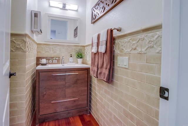 bathroom with vanity, a wainscoted wall, wood finished floors, and tile walls
