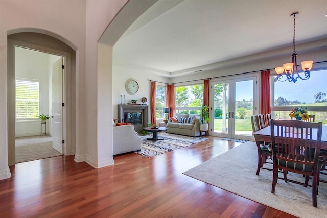 dining space with arched walkways, wood finished floors, baseboards, and an inviting chandelier