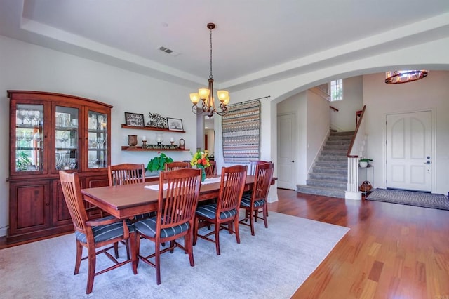 dining room featuring stairway, a notable chandelier, wood finished floors, and visible vents