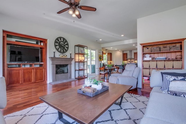 living room featuring a ceiling fan, wood finished floors, recessed lighting, and a fireplace with raised hearth