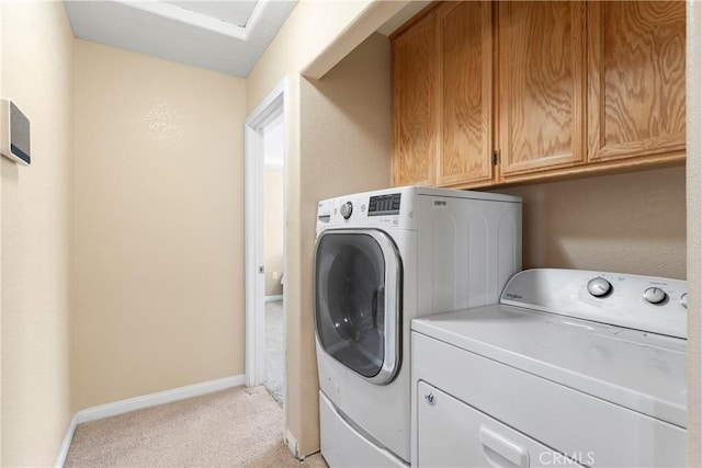 laundry area featuring cabinet space, independent washer and dryer, light colored carpet, and baseboards