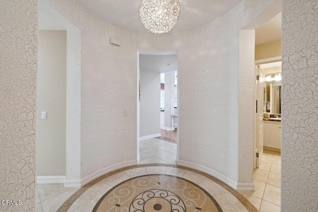1551 Windshore Way, Oxnard, CA 93035 - corridor featuring a textured wall, tile patterned flooring, a chandelier, inlaid floor details, and baseboards