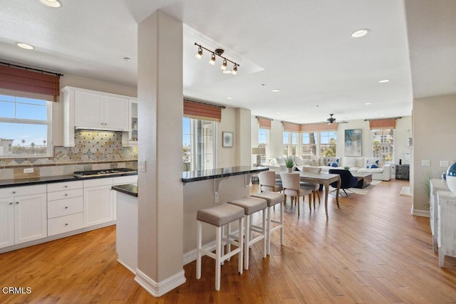 1551 Windshore Way, Oxnard, CA 93035 - kitchen with a kitchen bar, gas cooktop, dark countertops, light wood-style flooring, and white cabinetry