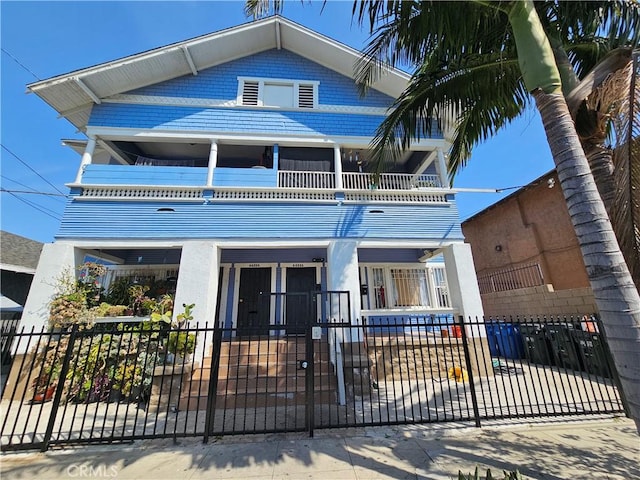 view of front of house with fence and a balcony