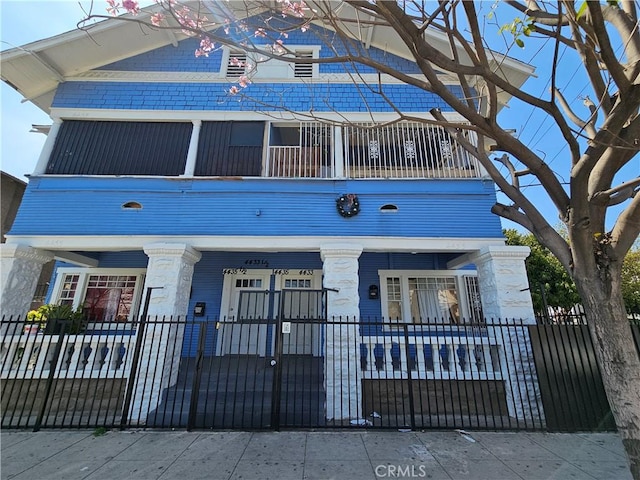 view of front of property with fence and a balcony
