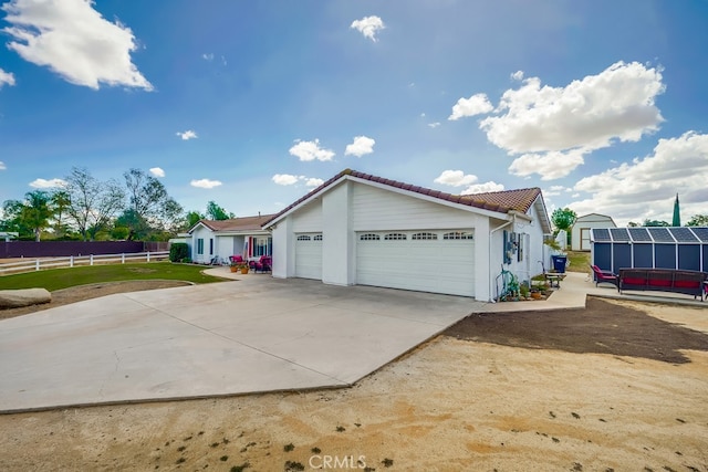 view of home's exterior with a garage, fence, concrete driveway, and a tile roof