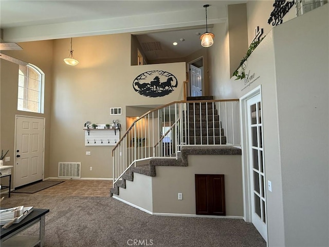 interior space featuring a high ceiling, carpet flooring, baseboards, and visible vents