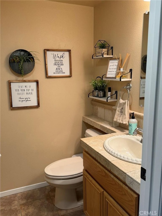 half bath with tile patterned floors, baseboards, toilet, and vanity