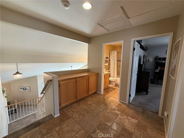 corridor featuring an upstairs landing, attic access, stone tile floors, and baseboards