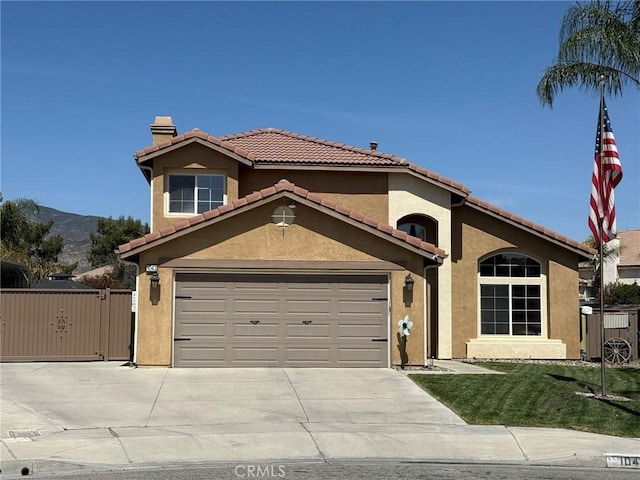 mediterranean / spanish-style home with stucco siding, a gate, concrete driveway, and a chimney