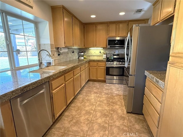 kitchen with decorative backsplash, a sink, tile counters, visible vents, and stainless steel appliances